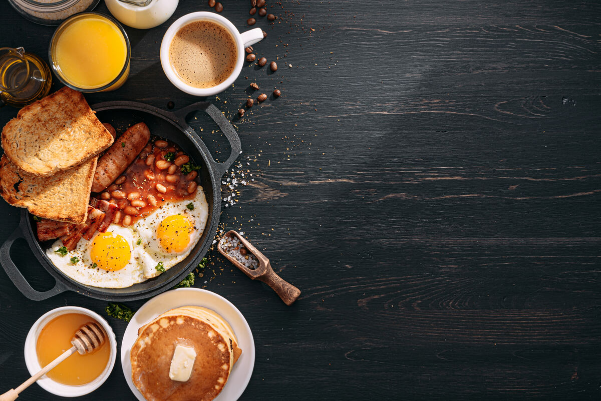 Breakfast buffet spread with eggs, bacon, pancakes, and coffee